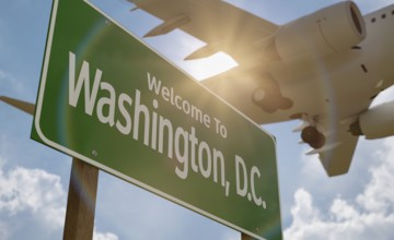 Welcome to washington D.C. road sign against a blue sky and clouds with low flying airplane above