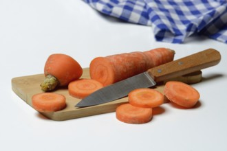 Carrot, carrot slices with kitchen knife on wooden board