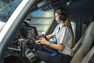 Confident female pilot using electronic flight bag while sitting in cockpit of small airplane