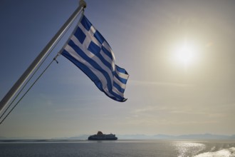Greek flag waving, with a ship in the background and sunny sky, crossing Rhodes to Symi, ferry,
