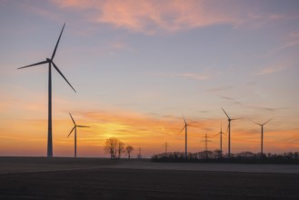 Wind farm at sunset, the sky is bathed in soft pink and orange, near Ulm, Swabian Alb,