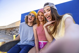Three joyful skaters enjoying a sunny day, capturing a fun selfie against a vibrant blue wall,