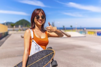 Young urban chinese woman gesturing confidence with thumb up in skateboard park