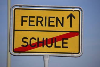 (Photomontage) Symbolic image summer holidays: Town exit sign with text HOLIDAYS and SCHOOL