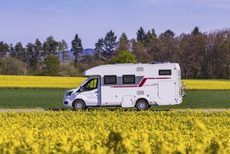 Country road with motorhome on the Swabian Alb with rape field in bloom. Erkenbrechtsweiler,