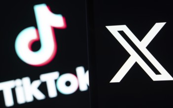 Twitter (X) logo is seen on a smartphone and Tiktok logo in the background