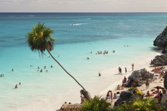 Tourists on the beach in front of the Mayan ruins of Tulum, Riviera Maya, Yucatan Peninsula,