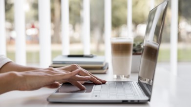 Side view businesswoman working with laptop having coffee