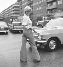 Fashion of the 1970s. A young woman wearing the typical fashion of the 1970s, wide legged trousers.