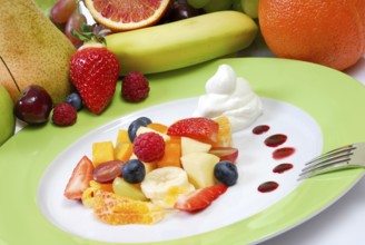 Fruit salad with cream arranged on a plate in front of fresh fruit
