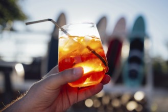 Orange slice and aperol spritz cocktail on a stone against the backdrop of a sandy beach. Man