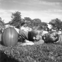 Rugby 1940. Three young rugby players lying in the grass on the rugby field, one holding the rugby