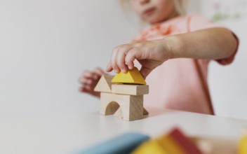 Little child girl playing wooden building blocks at home or kindergarten. Development and