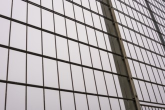 Close-up of a metal mesh wire fence, forming a regular grid pattern against a soft, overcast sky