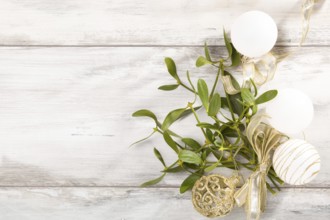 Branch of Mistletoe with ribbon and christmas balls on wooden background with copyspace. Christmas