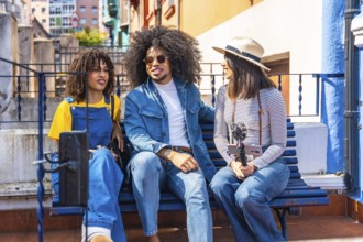 Three young content creators are recording a podcast outdoors, using a smartphone and microphone