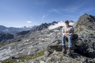Mountaineer resting on a rock, in rocky mountain landscape, at Col de Prafleuri, Valais Alps, Val