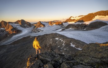 Mountaineers in front of a picturesque high mountain landscape at sunrise with alpenglow, glacier