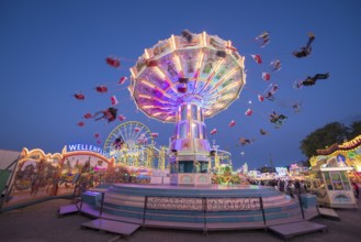An illuminated chain carousel turns at a fairground at night, chain carousel, spring festival,