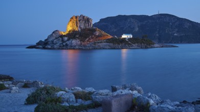 Impressive shining rock on an island at dusk with calm sea, Agios Stefanos Beach, Agios Stefanos