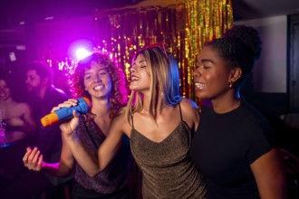 Three young women enjoy a lively karaoke night, singing into a microphone with colorful lights and