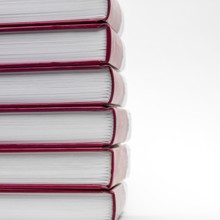Stacked books with red spines creating a minimalist display against a white background