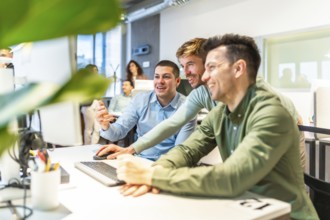 Programmers collaborating on code in a bright, modern office, showcasing teamwork and innovation in