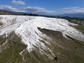 White limestone hills in a natural setting under a blue sky with clouds, aerial view, sinter