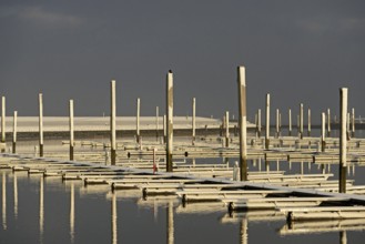 Winter day, onset of winter, morning sun shining on the snow-covered jetties in the marina, North