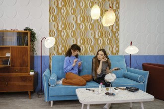 Two young women are engaged in a casual conversation about makeup while sitting on a stylish blue