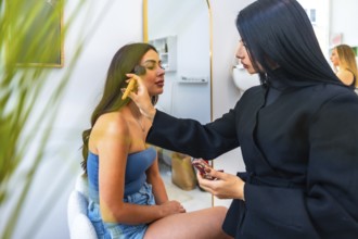 Professional makeup artist applying foundation on a client's face using a brush, enhancing her