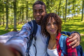 Young hikers with backpacks enjoying a sunny summer day, capturing a joyful selfie portrait amidst