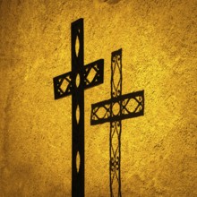 Shadow cast by one ornate cross on a textured wall at sunset illuminates the religious significance