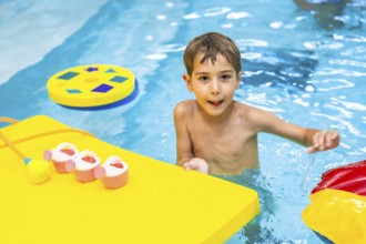 Happy boy enjoying playful moments with colorful floating toys in a swimming pool, embracing the
