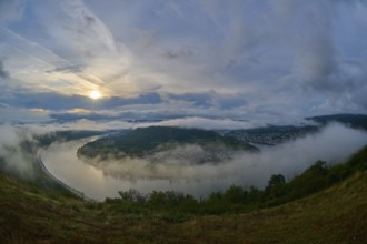 River landscape in a bend with misty hills and cloudy sky illuminated by the sunrise, summer, Rhine