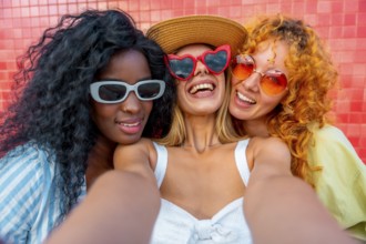 Three cheerful women with sunglasses are taking a selfie, smiling and enjoying their time together