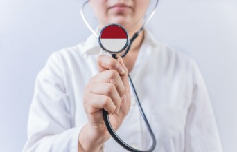 Female doctor holding stethoscope with Monaco flag. National health system of Monaco