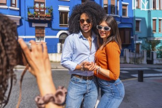 Young photographer taking pictures of a happy tourist couple posing in a colorful street during a