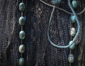 Detailed close-up of a fishing net with ropes and blue-green floats, harbour, Ringkøbing,