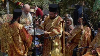 Priests with liturgical jewellery and robes perform a religious ritual with incense and prayers,