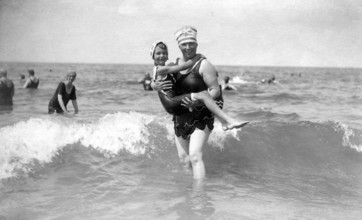 Woman in the water with a child, 1920s, A woman and a child in swimwear smiling in the sea,