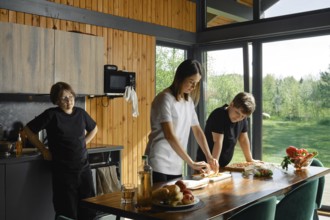 Mother skillfully prepares healthy food on a wooden table while two children watching. Natural