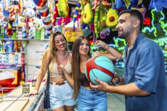 Happy friends enjoying time at an amusement park, playing a basketball game and celebrating their