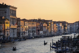 View of the Grand Canal with gondoliers at sunset, picturesque evening mood with palazzos on the