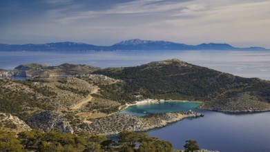View of a coastal landscape with hilly vegetation and blue water, Holy Week, Bay of Panormitis,