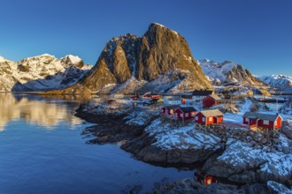 Fishermen's Village in front of snowy mountain range at the coastline in winter, Lofoten, Norway