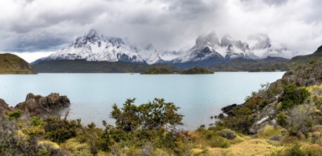 Cloudy mountain range Cuernos del Paine, shore of the blue lake Lago Pehoe in the evening light,