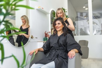 Hairdresser styling hair of smiling customer sitting in armchair in a modern and bright beauty