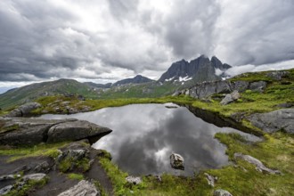 Small lake in mountain landscape, hike to Barden mountain, Breidtind mountain peak behind, Senja,