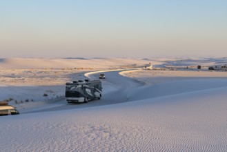 Vehicles being driven on cleared roads through the white gypsum dunes at White Sands National Park